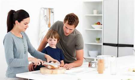simsearch:400-05744780,k - Lovely woman cutting bread for her son ad husband in the kitchen Stock Photo - Budget Royalty-Free & Subscription, Code: 400-04287058