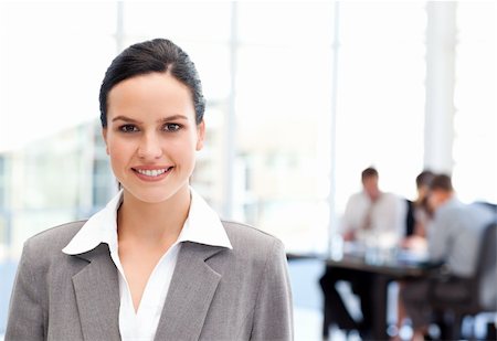 Adorable businesswoman standing in front of her team while working in the background Stock Photo - Budget Royalty-Free & Subscription, Code: 400-04287083