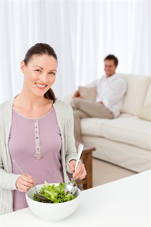 simsearch:400-05744780,k - Pretty woman preparing a salad in the kitchen for her boyfriend sitting in the living room Stock Photo - Budget Royalty-Free & Subscription, Code: 400-04287247