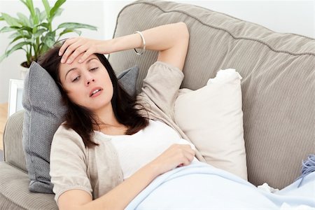 feeble - Indisposed woman feeling her temperature while resting on the sofa at home Stock Photo - Budget Royalty-Free & Subscription, Code: 400-04287315