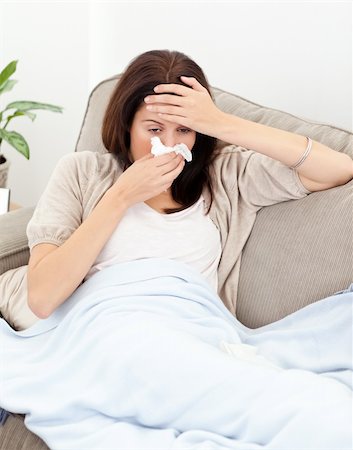 feeble - Tired woman feeling her temperature while blowing her nose on the sofa Stock Photo - Budget Royalty-Free & Subscription, Code: 400-04287317
