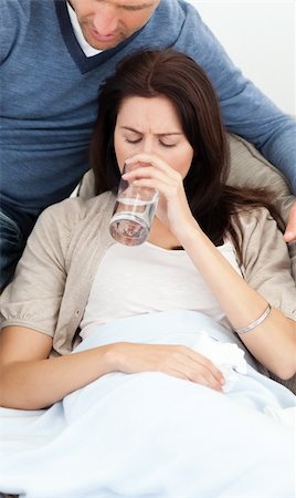 feeble - Sick woman drinking water lying on the sofa with her boyfriend Foto de stock - Super Valor sin royalties y Suscripción, Código: 400-04287318