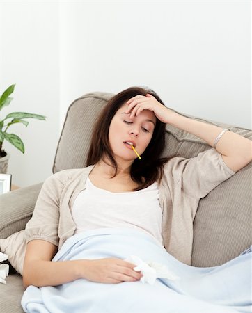 feeble - Sick woman taking her temperature with a thermometer on the sofa at home Photographie de stock - Aubaine LD & Abonnement, Code: 400-04287320