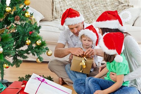 simsearch:400-04193348,k - Family unwrapping gifts near the christmas tree Stock Photo - Budget Royalty-Free & Subscription, Code: 400-04296615
