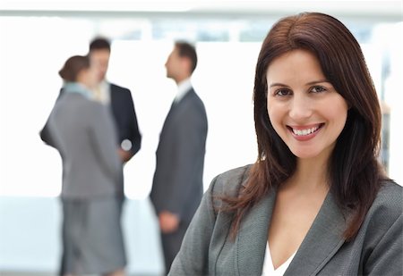 Happy businesswoman posing while her team discussing on the background Stock Photo - Budget Royalty-Free & Subscription, Code: 400-04296694