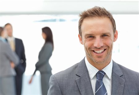 simsearch:400-05746962,k - Happy businessman posing in front of his team while working on the background Stock Photo - Budget Royalty-Free & Subscription, Code: 400-04296704