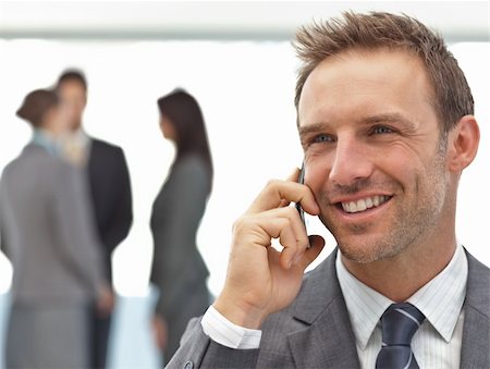 simsearch:400-05746962,k - Happy businessman on the phone while his team working on the background Stock Photo - Budget Royalty-Free & Subscription, Code: 400-04296706