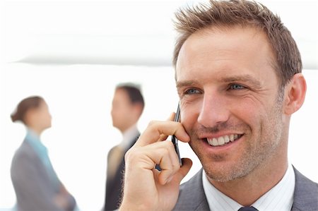 simsearch:400-05746962,k - Handsome businessman on the phone while his partners standing on the background Stock Photo - Budget Royalty-Free & Subscription, Code: 400-04296719