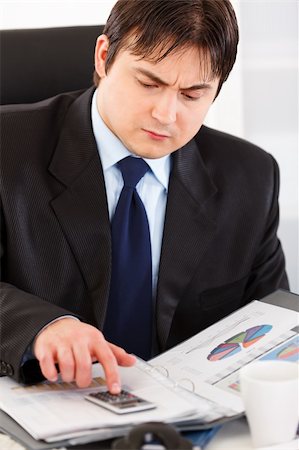 simsearch:400-05748170,k - Serious modern business man sitting at office desk and working  with financial documents Stock Photo - Budget Royalty-Free & Subscription, Code: 400-04305071