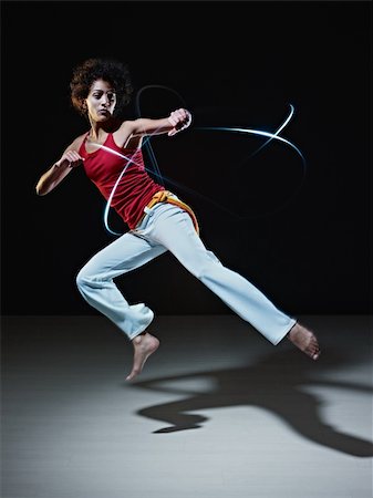 young adult latin american female doing capoeira flying kick in gym, with streaks of led lights all around. Vertical shape, full length, front view, copy space Stock Photo - Budget Royalty-Free & Subscription, Code: 400-04319620