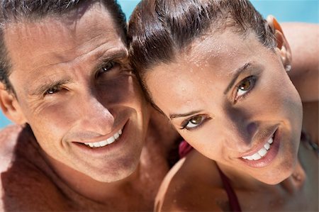 simsearch:400-07516179,k - Close up portrait of a beautiful happy man and woman couple in a sun bathed swimming pool smiling with perfect teeth. Stock Photo - Budget Royalty-Free & Subscription, Code: 400-04310598