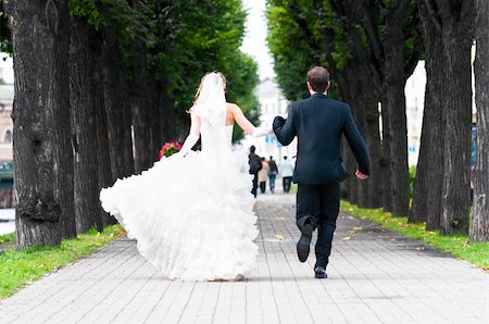 simsearch:400-04636190,k - bride and groom is running with joined hands on city park road Stock Photo - Budget Royalty-Free & Subscription, Code: 400-04335666