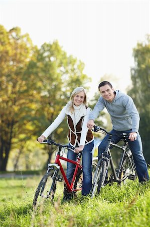 simsearch:400-05755734,k - Young smiling couple on bicycles in the park Photographie de stock - Aubaine LD & Abonnement, Code: 400-04336532