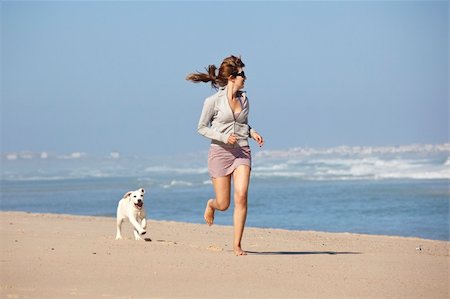 dog running on a beach - Young woman running and playing with her cute labrador retriever puppy Stock Photo - Budget Royalty-Free & Subscription, Code: 400-04337015