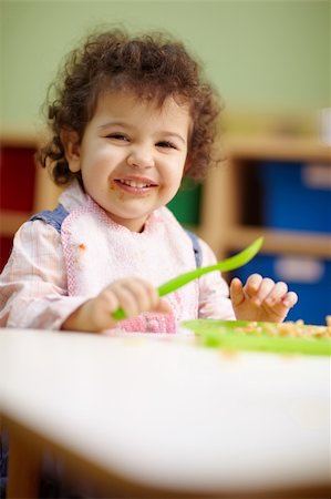 hispanic female preschooler eating pasta and smiling at camera. Vertical shape, waist up, copy space Foto de stock - Super Valor sin royalties y Suscripción, Código: 400-04344270