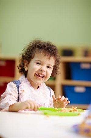 hispanic female preschooler eating pasta and smiling at camera. Vertical shape, waist up, copy space Foto de stock - Super Valor sin royalties y Suscripción, Código: 400-04349785