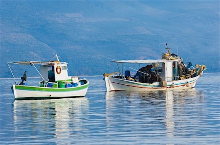 simsearch:400-05676936,k - Two fishing boats floating peacefully in a bay in southern Greece, while fishermen are working on their catch Stock Photo - Budget Royalty-Free & Subscription, Code: 400-04368710