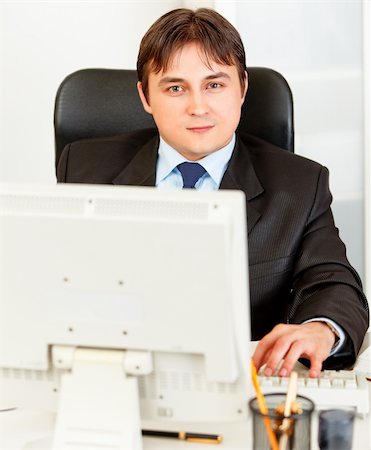 simsearch:400-05748165,k - Modern business man sitting at office desk and working on pc Foto de stock - Super Valor sin royalties y Suscripción, Código: 400-04361490