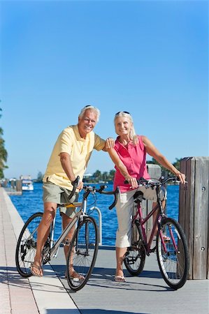 Happy senior man and woman couple together cycling on bicycles with bright clear blue sky by a river or sea Stock Photo - Budget Royalty-Free & Subscription, Code: 400-04362362