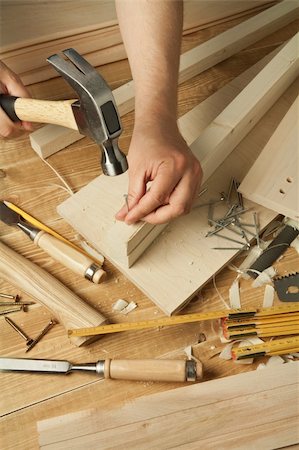 Wooden workshop table with tools. Man's arms hammering a nail Stock Photo - Budget Royalty-Free & Subscription, Code: 400-04378186