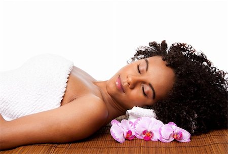 simsearch:400-05318677,k - Beautiful happy peaceful sleeping woman at a day spa, laying on bamboo massage table with head on pillow wearing a towel and orchid flowers around, isolated. Stock Photo - Budget Royalty-Free & Subscription, Code: 400-04379982