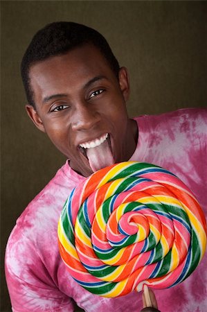 Smiling African-American licks an oversized colorful lollipop Stock Photo - Budget Royalty-Free & Subscription, Code: 400-04382066