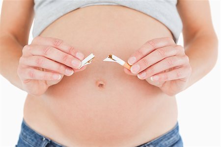 Young pregnant woman holding a broken cigarette while standing against a white background Stock Photo - Budget Royalty-Free & Subscription, Code: 400-04406027