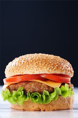 simsearch:400-06090558,k - Cheeseburger with tomatoes and lettuce on black background Stock Photo - Budget Royalty-Free & Subscription, Code: 400-04406558