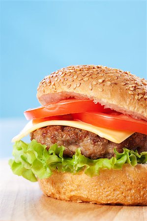 simsearch:400-06090558,k - Cheeseburger with tomatoes and lettuce on a wooden table with blue background Stock Photo - Budget Royalty-Free & Subscription, Code: 400-04406564