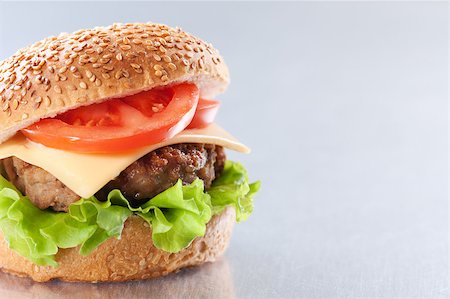 simsearch:400-06090558,k - Cheeseburger with tomatoes and lettuce on grey background Stock Photo - Budget Royalty-Free & Subscription, Code: 400-04406561