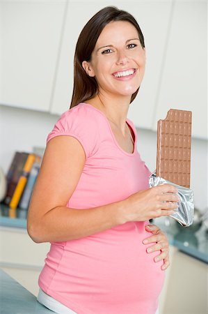 Pregnant woman in kitchen with large chocolate bar smiling Foto de stock - Super Valor sin royalties y Suscripción, Código: 400-04400753