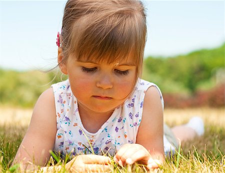 simsearch:400-04416781,k - Little pensive girl lying on grass in the park and looking at blade Stock Photo - Budget Royalty-Free & Subscription, Code: 400-04416787