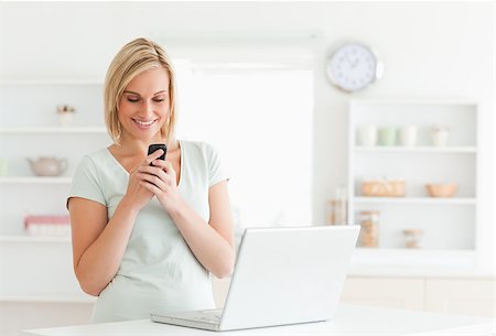 small shop interior - Cute woman smiling at her mobile in the kitchen Stock Photo - Budget Royalty-Free & Subscription, Code: 400-04417461