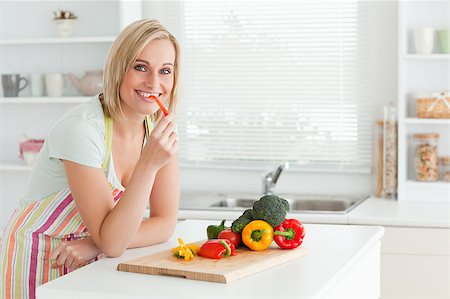 Portrait of a woman eating red peppers in kitchen Stock Photo - Budget Royalty-Free & Subscription, Code: 400-04417812
