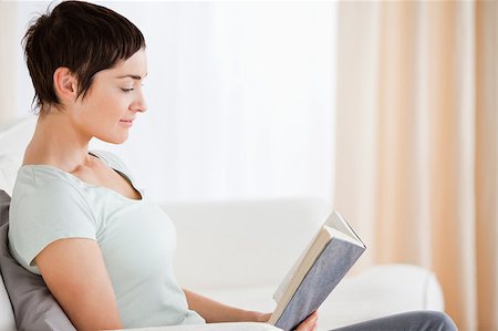 simsearch:400-04418460,k - Short-haired woman reading a book in her living room Stock Photo - Budget Royalty-Free & Subscription, Code: 400-04410674