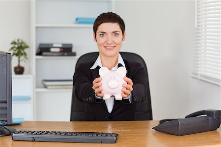 simsearch:6108-05874788,k - Smiling office worker holding a piggybank in her office Foto de stock - Super Valor sin royalties y Suscripción, Código: 400-04410885