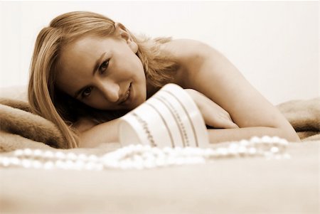 Young blonde woman lying on the bed in the morning. Shallow depth of field. Coffee cup is out of focus and the model is in focus. Photographie de stock - Aubaine LD & Abonnement, Code: 400-04437094