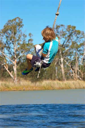 a boy is swinging on a rope over a river in summer Photographie de stock - Aubaine LD & Abonnement, Code: 400-04447151