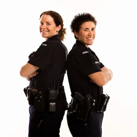 female police officer happy - Portrait of two mid adult Caucasian policewomen standing back to back looking over their shoulders and smiling at viewer. Photographie de stock - Aubaine LD & Abonnement, Code: 400-04468897