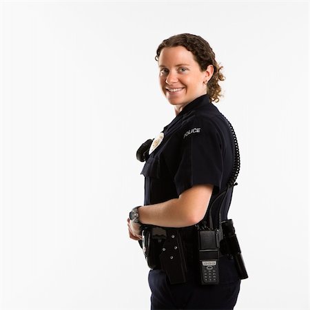 female police officer happy - Portrait of mid adult Caucasian policewoman standing with hand on gun holster looking over shoulder at viewer smiling. Photographie de stock - Aubaine LD & Abonnement, Code: 400-04468892