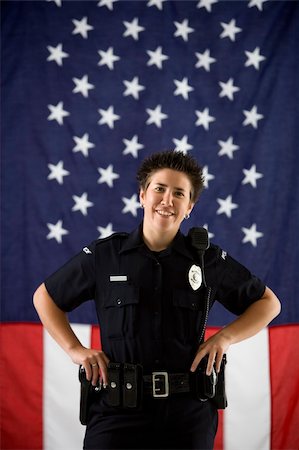 female police officer happy - Portrait of mid adult Caucasian policewoman standing with hands on holster and American flag as backdrop smiling at viewer. Photographie de stock - Aubaine LD & Abonnement, Code: 400-04468902