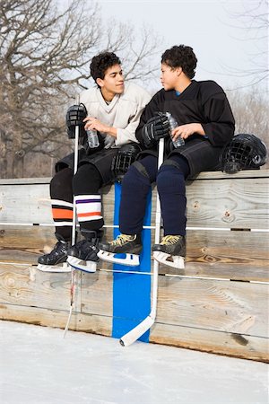 Two boys in ice hockey uniforms sitting on ice rink sidelines talking to eachother. Stock Photo - Budget Royalty-Free & Subscription, Code: 400-04471037