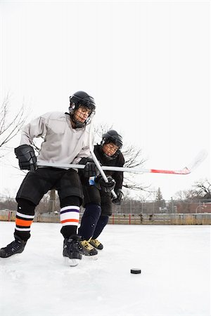 Two boys in ice hockey uniforms playing hockey on ice rink. Stock Photo - Budget Royalty-Free & Subscription, Code: 400-04471032