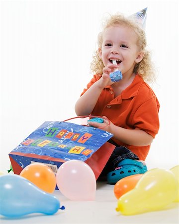 simsearch:400-04847852,k - Adorable little three year old boy wearing party hat sitting with balloons with hand in a gift bag blowing on a party favor Stock Photo - Budget Royalty-Free & Subscription, Code: 400-04498783