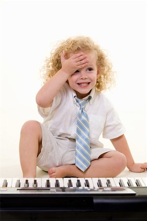 Adorable little three year old boy with long curly blond hair wearing white shirt and tie sitting in front of a piano keyboard with hand on forhead Stock Photo - Budget Royalty-Free & Subscription, Code: 400-04499370