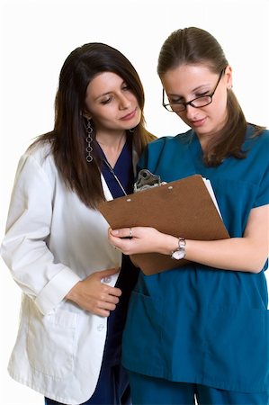 simsearch:400-07411030,k - Two woman healthcare workers one wearing a doctors lab coat the other in scrubs both looking over a patient chart standing on white Stock Photo - Budget Royalty-Free & Subscription, Code: 400-04501767