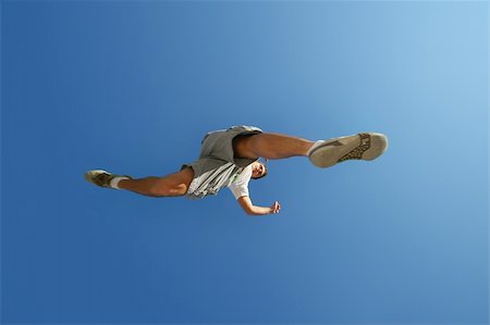 young man jumping over camera over blue sky Stock Photo - Budget Royalty-Free & Subscription, Code: 400-04513580