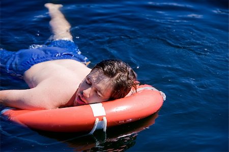 A swimmer laying exhausted on a life saving buoy Stock Photo - Budget Royalty-Free & Subscription, Code: 400-04532944