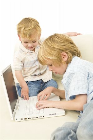 Two young children using a laptop while sitting on a settee Stock Photo - Budget Royalty-Free & Subscription, Code: 400-04544150