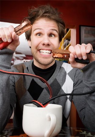 simsearch:400-04748544,k - Young man holding jumper cables coming out of coffee mug Stock Photo - Budget Royalty-Free & Subscription, Code: 400-04554625